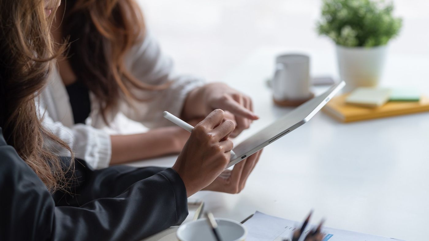 Two professionals review a plan together on a tablet.